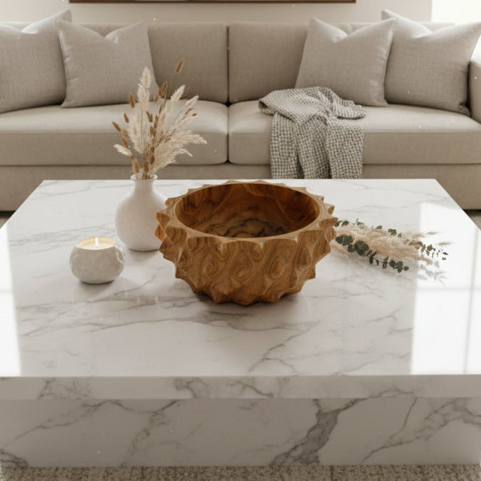 Wooden bowl with leaf-like carvings on a wooden surface