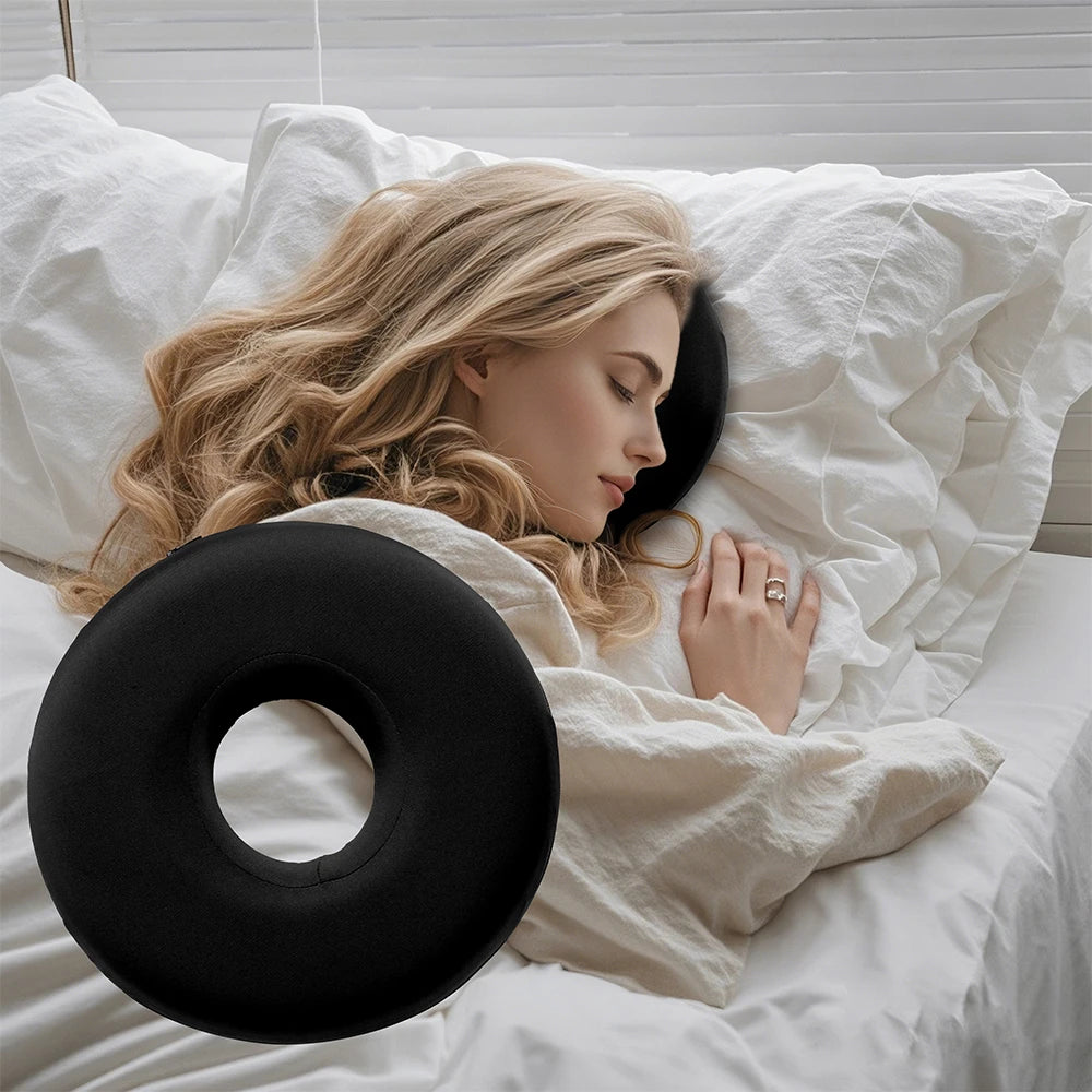 Woman lying in bed with a black donut-shaped pillow